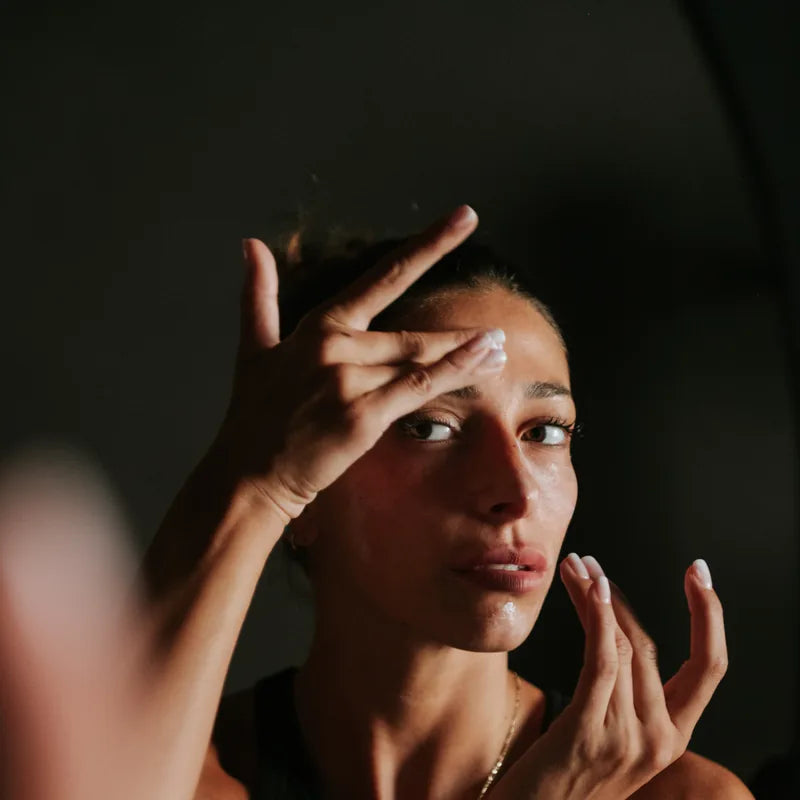Una donna che applica la crema viso con le dita